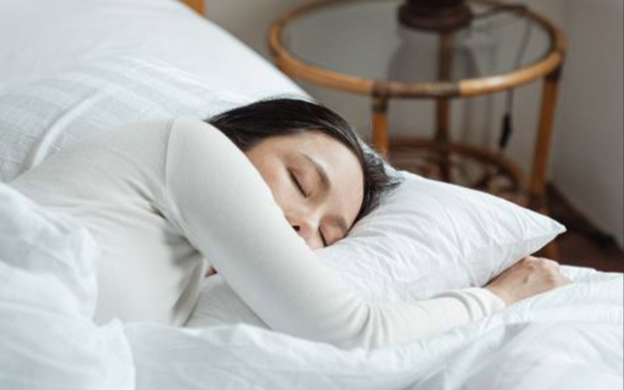 Conseils sommeil : femme qui dort paisiblement sur un lit